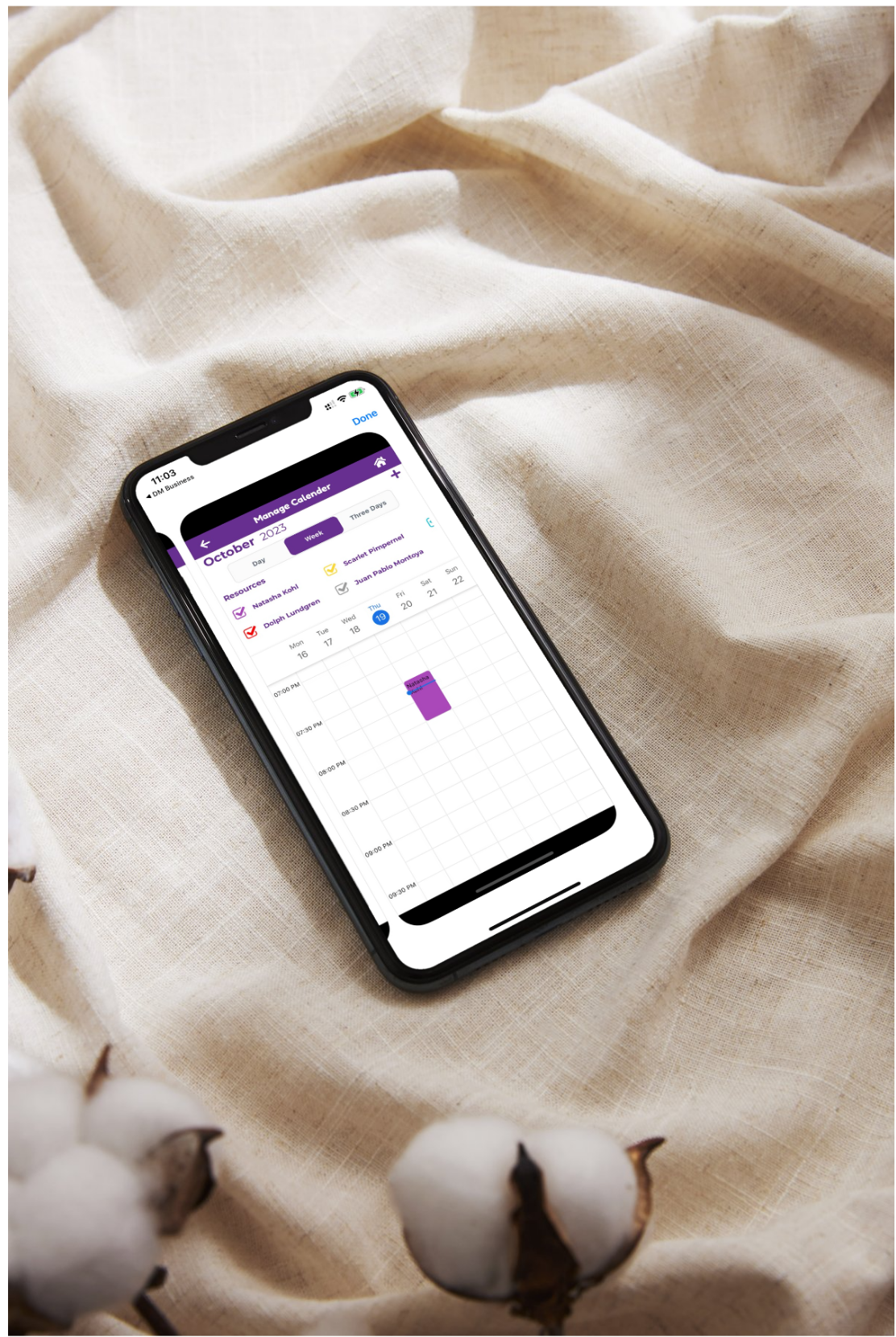 A phone displaying a digital booking calendar on a soft fabric background."